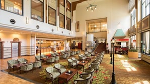 A spacious hotel lobby with multiple seating areas, a staircase, and a bar. - Dogo Onsen Hotel Tsubakikan (Matsuyama)