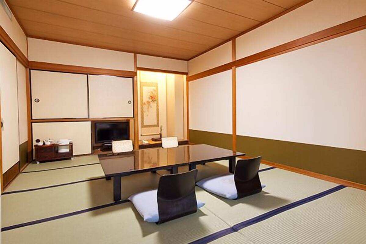 Una habitación tradicional japonesa con suelo de tatami, una mesa baja y cojines.