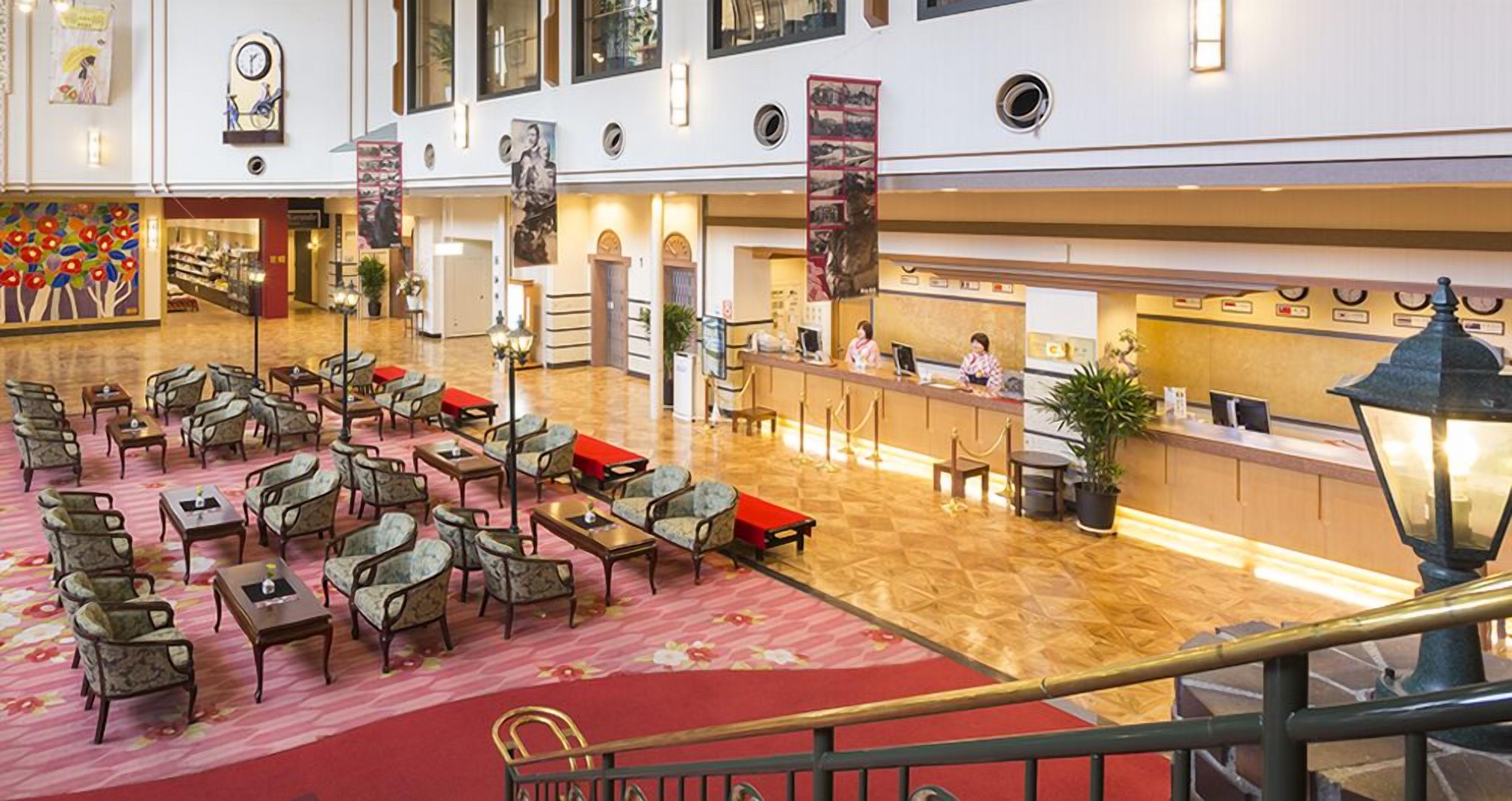 A hotel lobby with multiple seating areas, a reception desk, and a staircase.