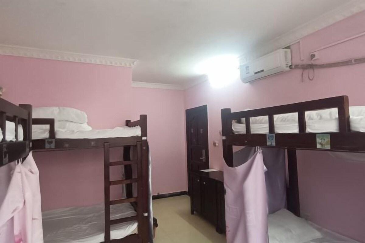 Una habitación con literas, un escritorio pequeño y un equipo de aire acondicionado.