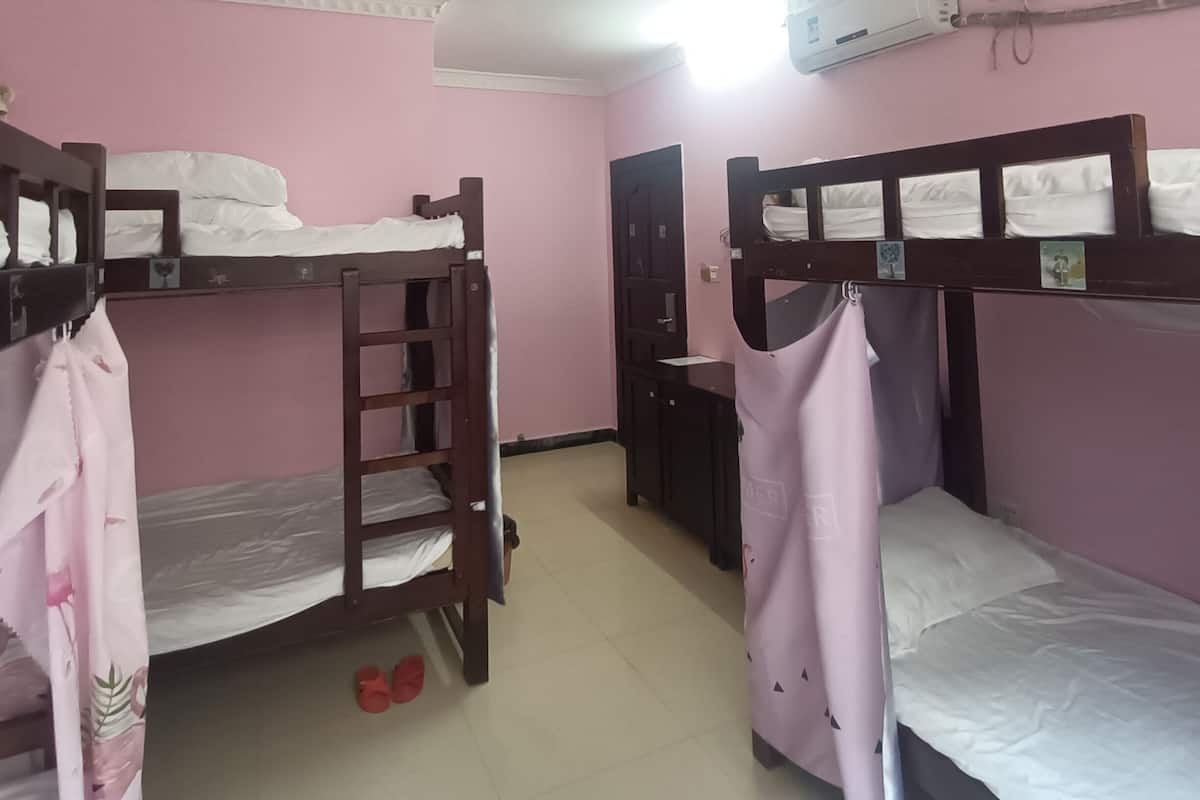 A room with bunk beds, a wardrobe, and an air conditioning unit.