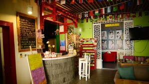 A cozy interior with a reception desk, seating area, and a wall decorated with flags and pictures. - How Flower Hostel Yangshuo (Guilin)