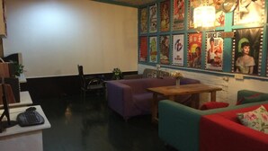 A cozy room with a seating area, a small table, and a projector screen. - How Flower Hostel Yangshuo (Guilin)
