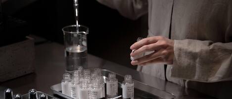 Une personne manipule de petites bouteilles et un plateau contenant plusieurs bouteilles sur une surface métallique.
