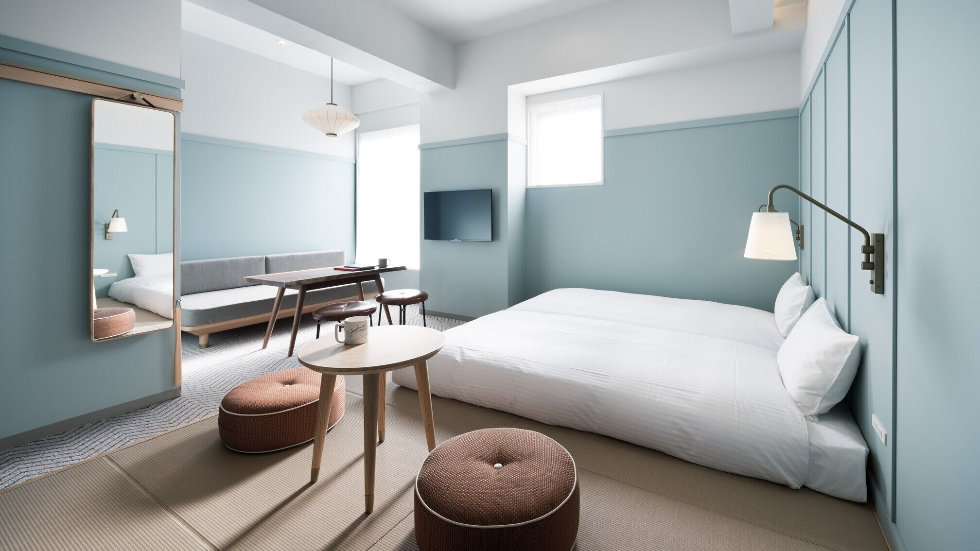 Quarto de hotel moderno com cama, área de estar e televisão.