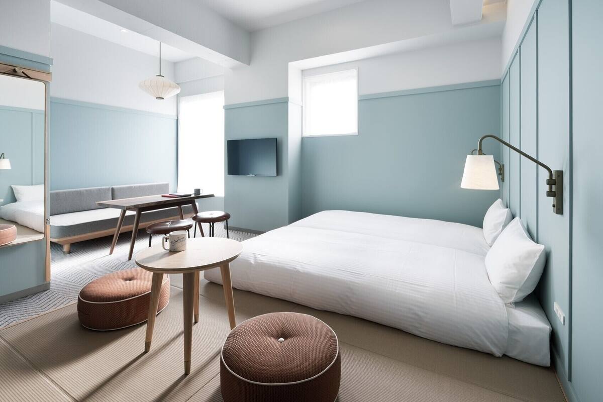 A modern hotel room with a bed, seating area, and a TV.