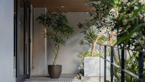 A modern building entrance with a potted tree, a sign reading "RAKURU KYOTO fawn.", and a metal railing with greenery. -  RAKURO Kyoto by THE SHARE HOTELS (Kyoto)