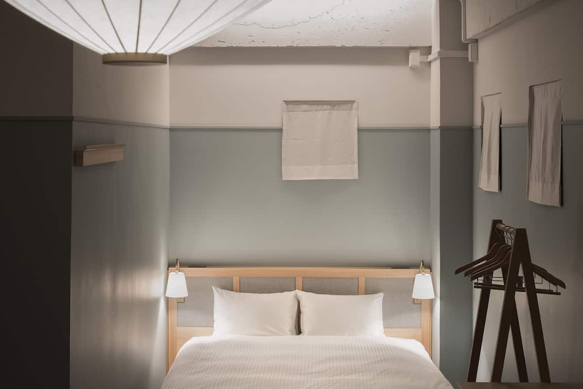 A hotel room with a large bed, two bedside lamps, a wooden headboard, a hanging towel, and a wooden chair.