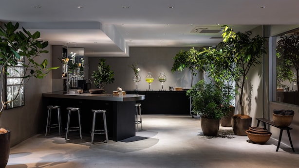 A modern kitchen with a central island, bar stools, and potted plants. -  RAKURO Kyoto by THE SHARE HOTELS (Kyoto)