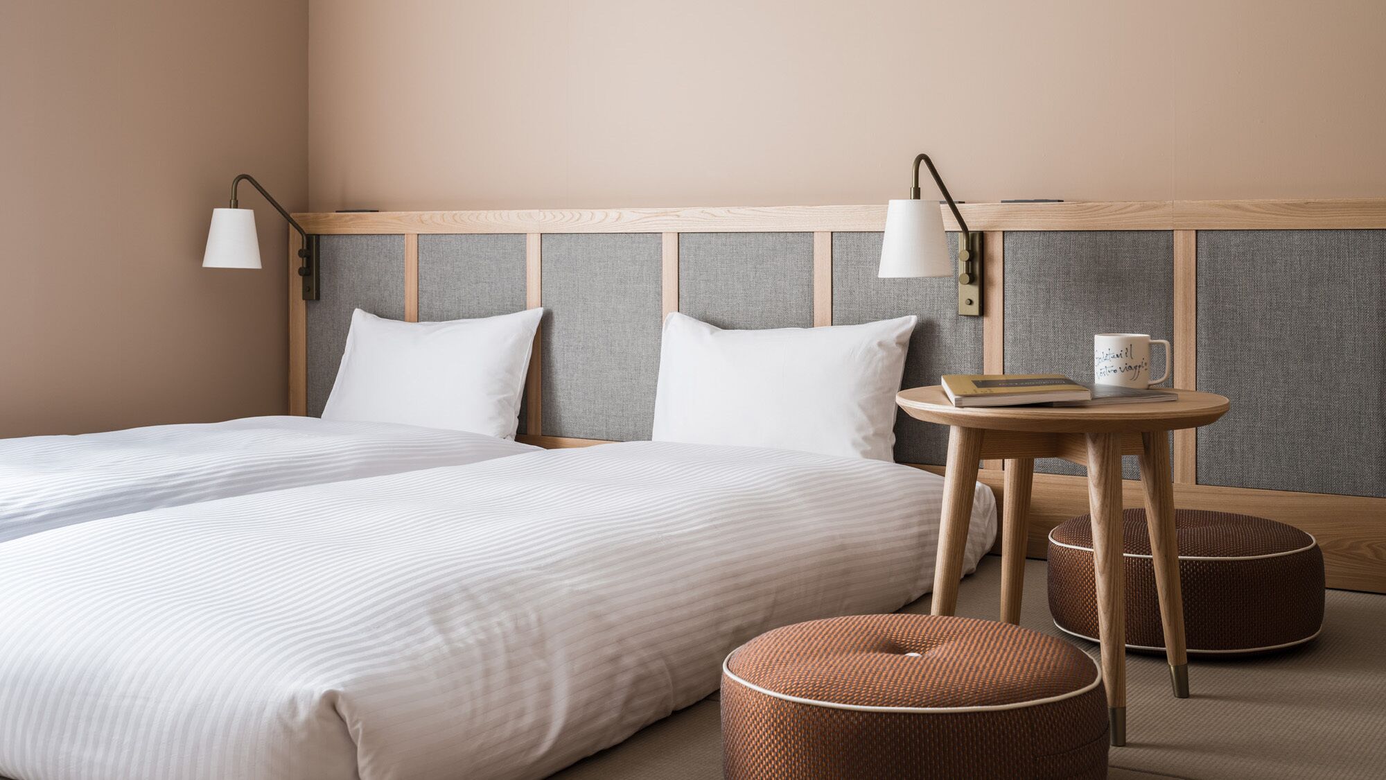 A hotel room with a large bed, two bedside tables, and a small round table with a book and mug.