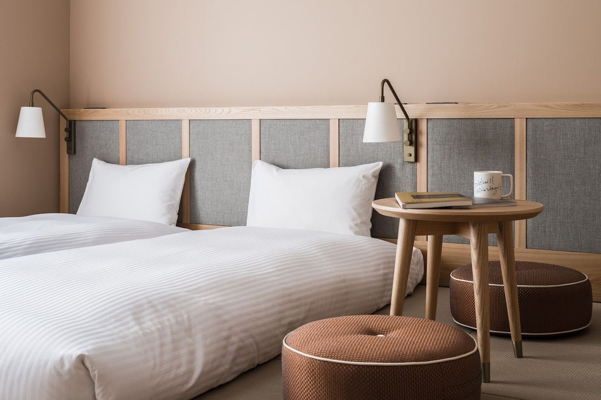 A hotel room with a large bed, two bedside tables, and a small round table with a book and mug.