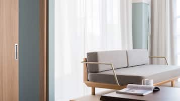 A modern hotel room with a wooden ceiling, a sofa, a table, and a chair.