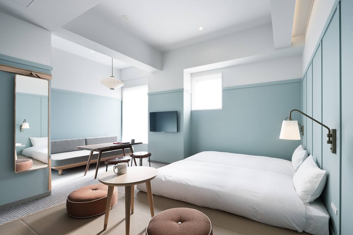 A modern hotel room with a large bed, a desk, a sofa, and a TV.
