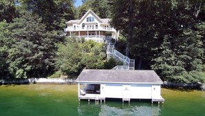 Uma casa com um cais que se projeta sobre um lago, rodeada por árvores densas.