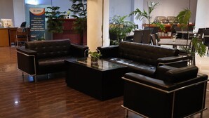 A lobby with leather sofas, a glass coffee table, and a reception desk. - Azza Hotel Palembang by Horison (Palembang)