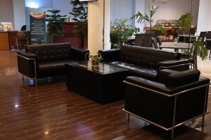Um lobby com sofás de couro, uma mesa de centro de vidro e um balcão de recepção.