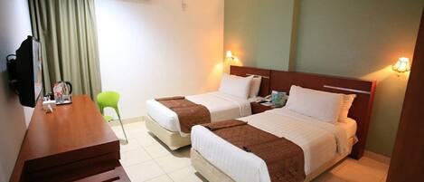 A hotel room with two beds, a desk, a chair, and a TV.