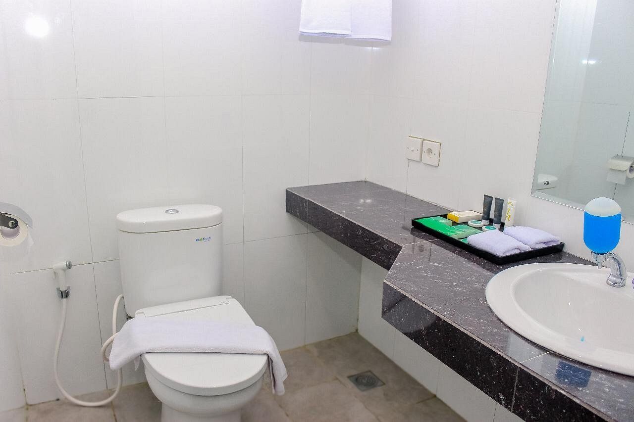 A bathroom with a toilet, sink, and mirror.
