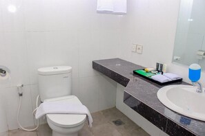 Um banheiro com vaso sanitário, pia e espelho.