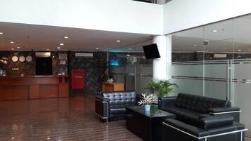 A modern lobby with a reception desk, seating area, and a large screen.