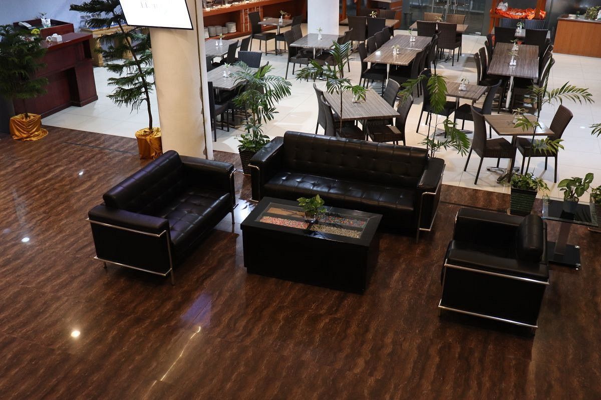 A spacious indoor area with multiple dining tables and chairs, a reception desk, and several potted plants.