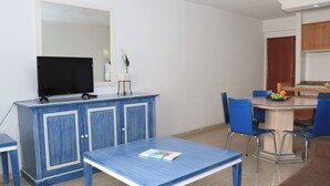 Ein Essbereich mit blauem Tisch, Stühlen und einem Fernseher auf einem Schrank.