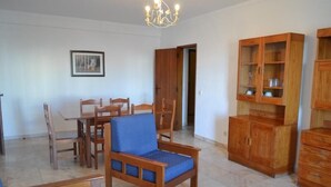 Ein Wohnzimmer mit Essbereich, Holzmöbeln und einer Deckenleuchte.