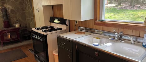 A compact kitchen with a stove, sink, and wooden cabinets.