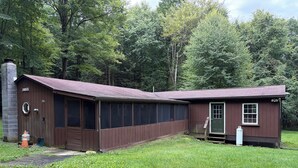 Un bâtiment en bois à deux étages, avec une façade marron, un porche couvert et un petit abri attenant.
