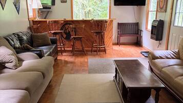 A living room with a fireplace, a television, a wooden bar, and a large window.