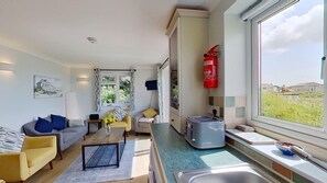 Un espace de vie compact comprenant un coin cuisine, un coin repas et une grande fenêtre donnant sur l’extérieur.