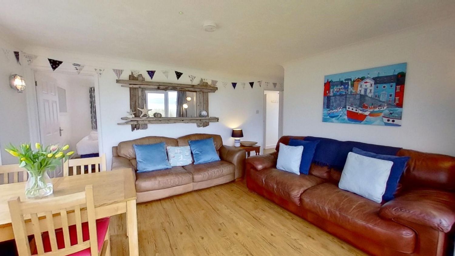 A living room with two sofas, a wooden dining table, and a painting on the wall.