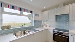 A kitchen with white cabinets, a blue-tiled backsplash, a stainless steel sink, a toaster, and a dishwasher.