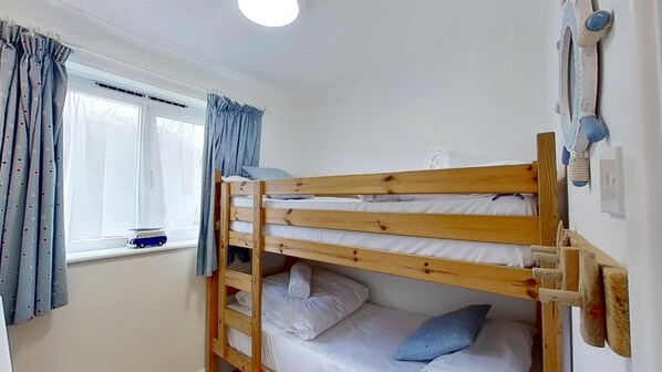 A bunk bed room with a window, curtains, and a small toy car on the sill.