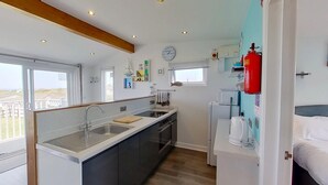 A compact kitchen with a sink, stove, and a clock on the wall.