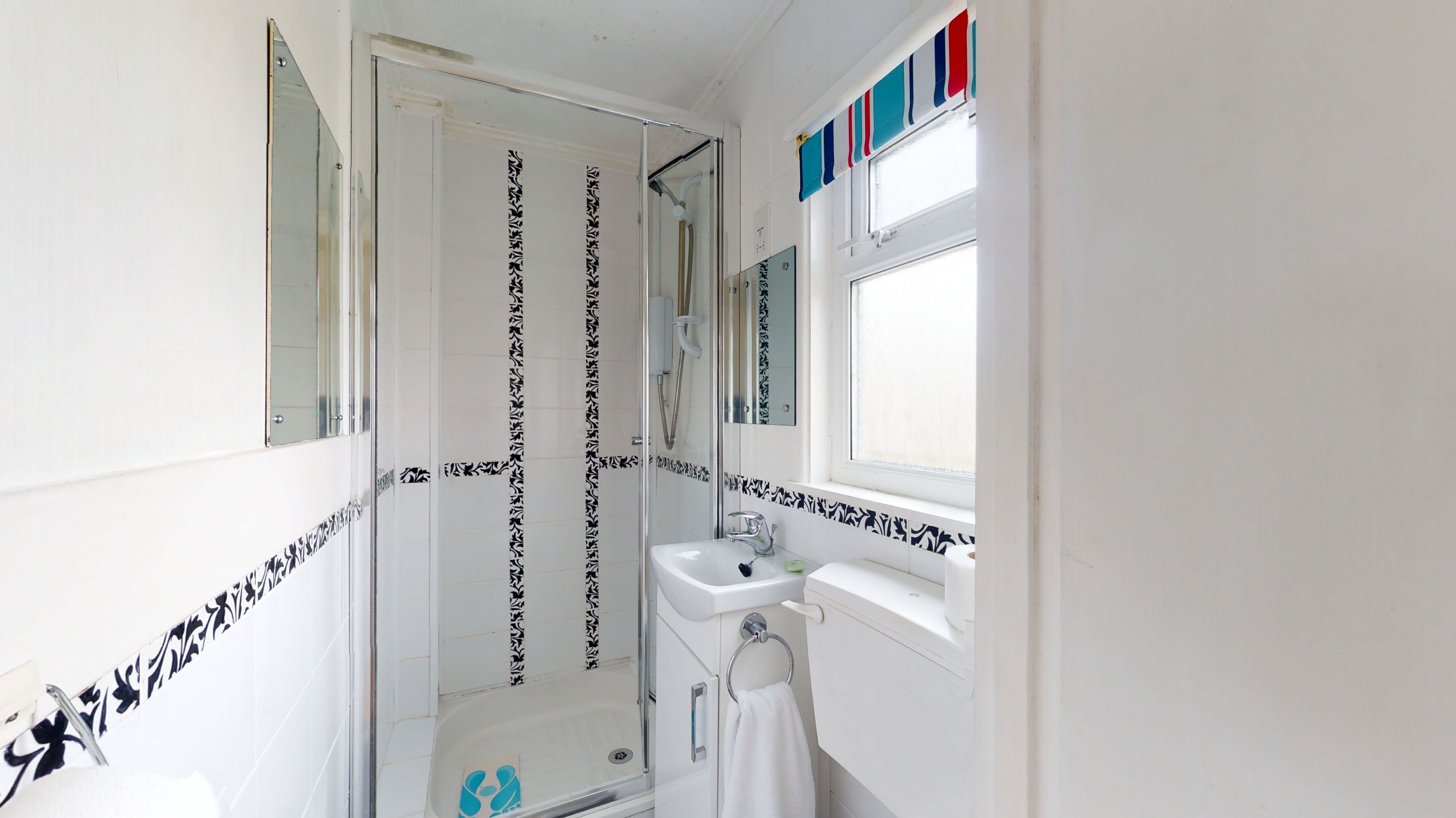 Een badkamer met een douche, een wastafel en een raam.