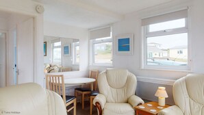Ett rum med ett matbord, två stolar, en soffa och en lampa.