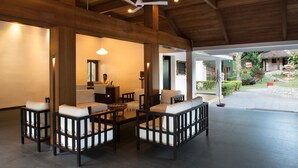 A spacious lobby with wooden beams, a ceiling fan, and a reception desk. - Cardamom County by Xandari (Peermade)