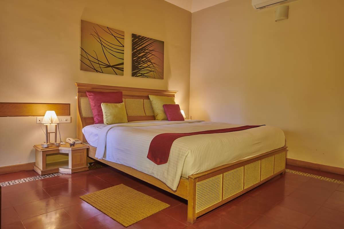 A neatly made bed with a wooden headboard, a bedside lamp, and a small bedside table.