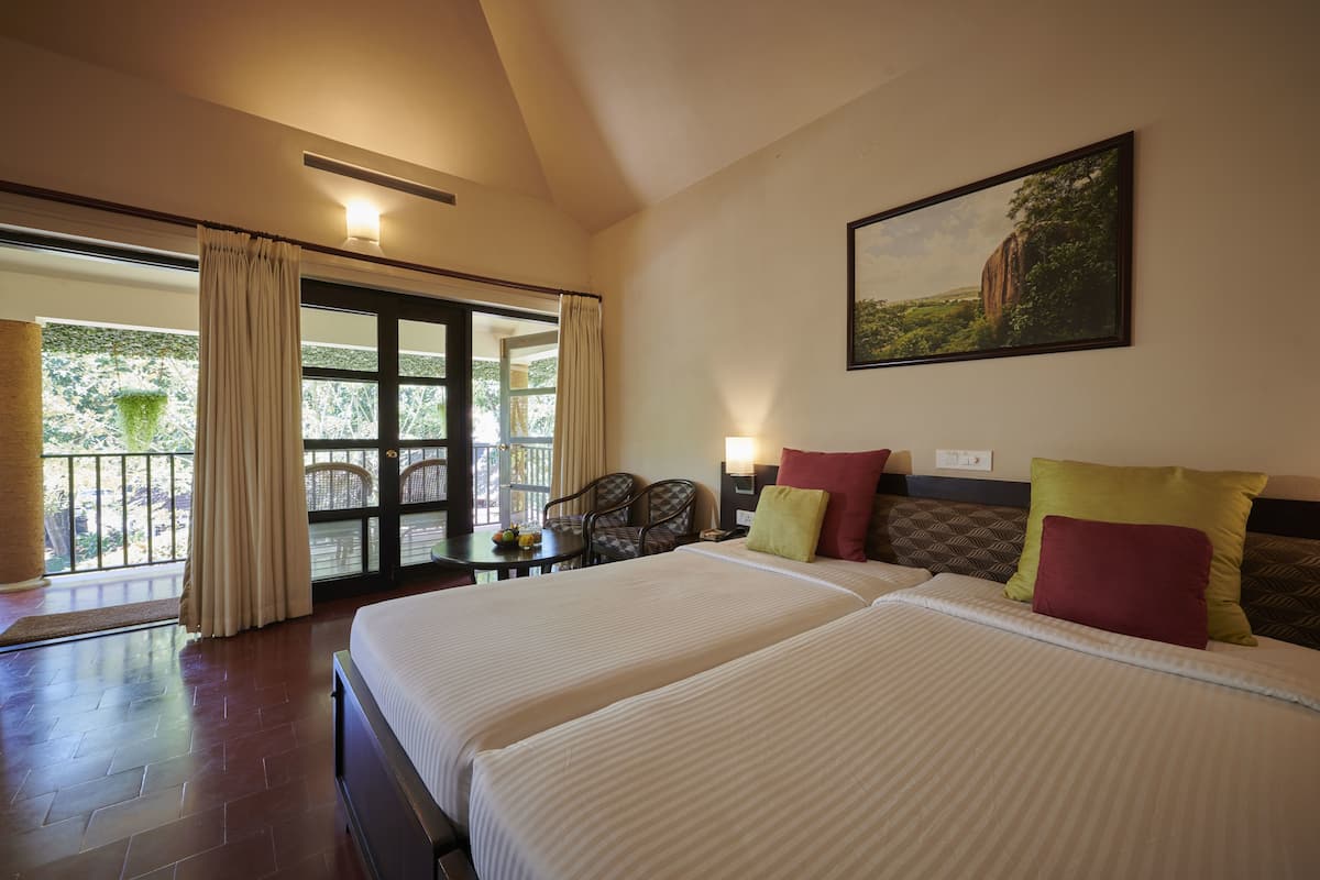 A hotel room with two beds, a dining table, chairs, a large window with curtains, and a painting on the wall.