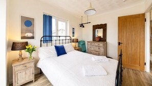 Un dormitorio con cama, cómoda, espejo, lámpara y ventana con cortinas.