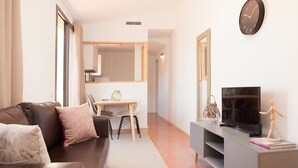 Un salon moderne comprenant un canapé, un téléviseur et un coin repas avec une table et des chaises.