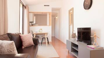 Una sala moderna con sofá, televisor y zona de comedor con mesa y sillas.