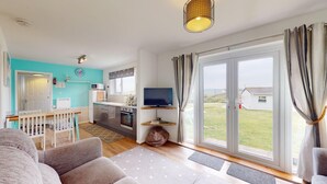 Ein modernes Wohnzimmer mit einer Couch, einem Fernseher und einer Küchenzeile mit Mikrowelle und Backofen.