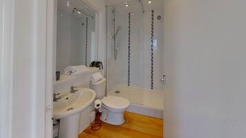 Een moderne badkamer met een douchecabine van glas, een wastafel en een toilet.