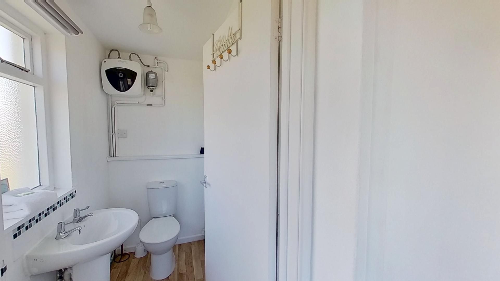Ein Badezimmer mit Toilette, Waschbecken und Wand-Wasserbereiter.