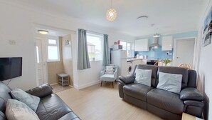 En moderne stue med en sofa, et fjernsyn og et lille bord.