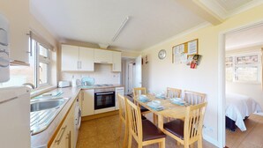 Una cocina compacta con comedor, lavadora y una cama en la habitación contigua.