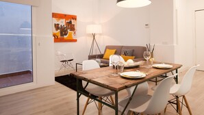 A dining area with a wooden table, white chairs, and a black pendant light. - Stylish apartment in city center B3 (Barcelona)