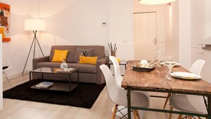 A modern living room with a sofa, coffee table, and dining table set up for a meal. - Stylish apartment in city center B3 (Barcelona)